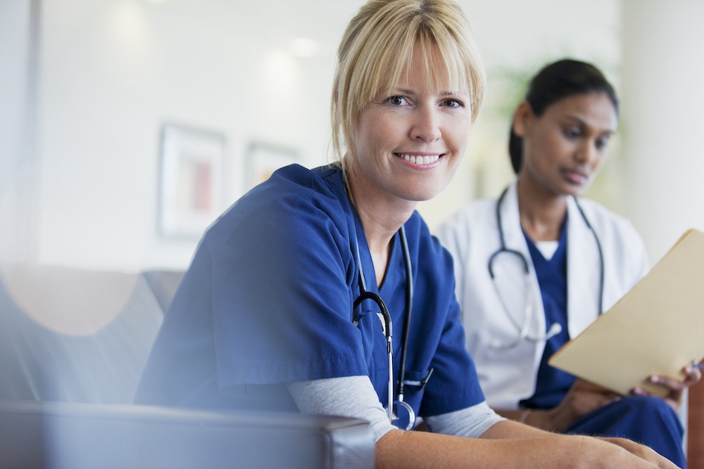 Portrait of smiling nurse sitting with doctor in hospital